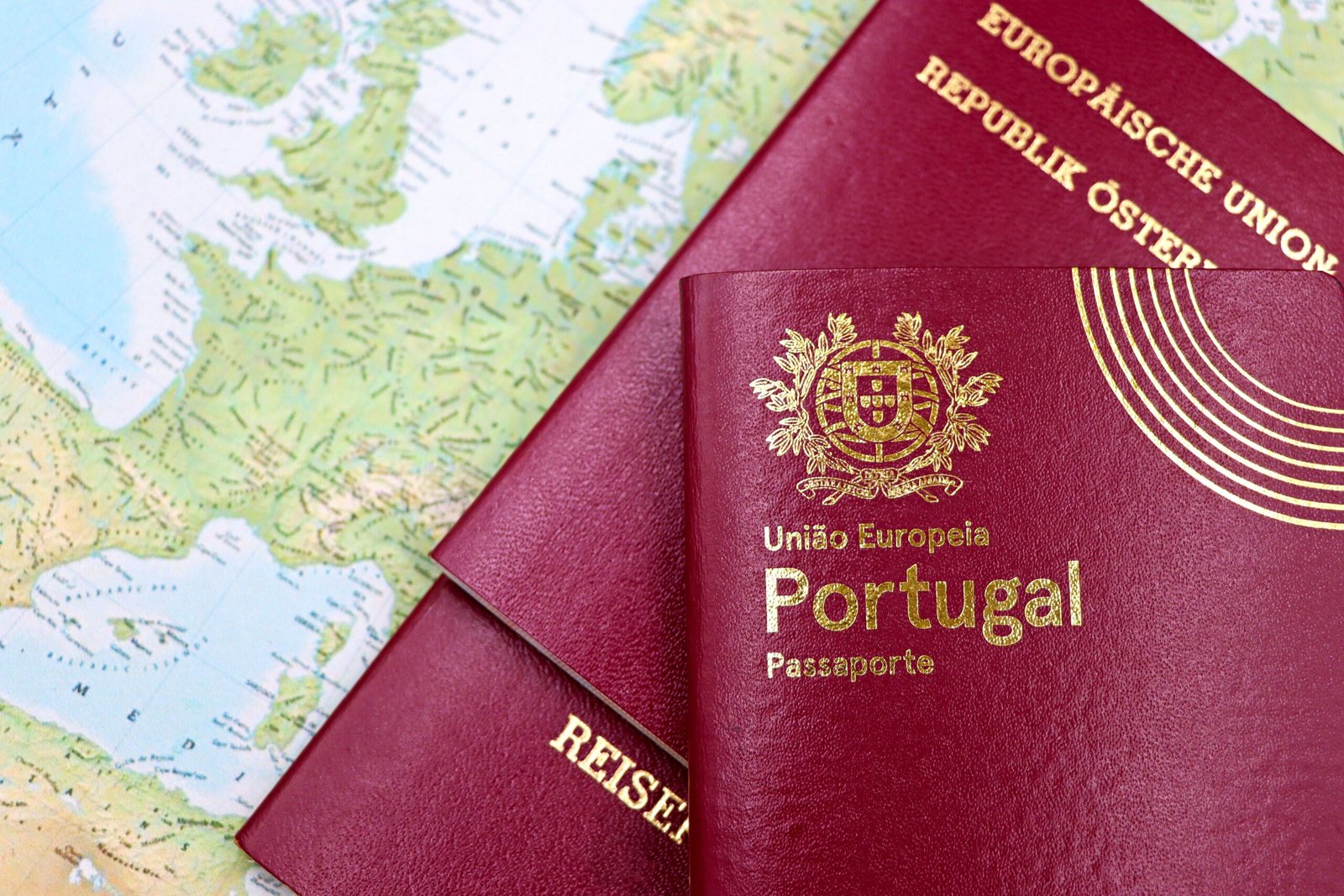Passeport portugais et documents de voyage posés sur une carte du monde, à côté d’un guide sur la carte bleue européenne.